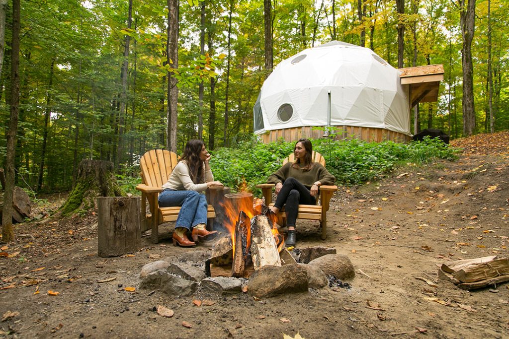 Campers by a fire beside a geodesic dome at Glen Oro Farm