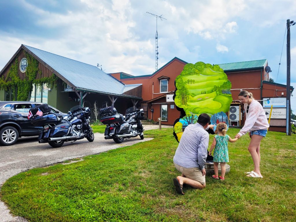 family of three looks at art tree in front of HQ restaurant and motor bikes
