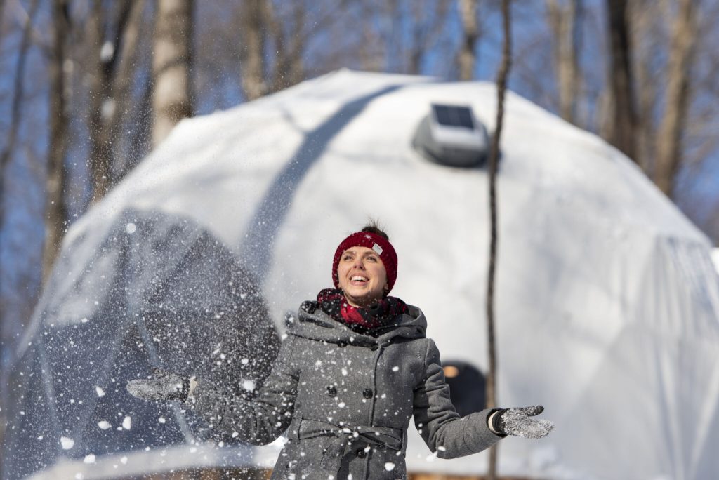 Person throwing snow beside an illuminated winter dome