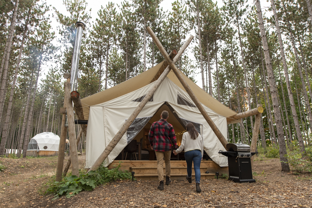 Visitors outside a glamping tent in the forest