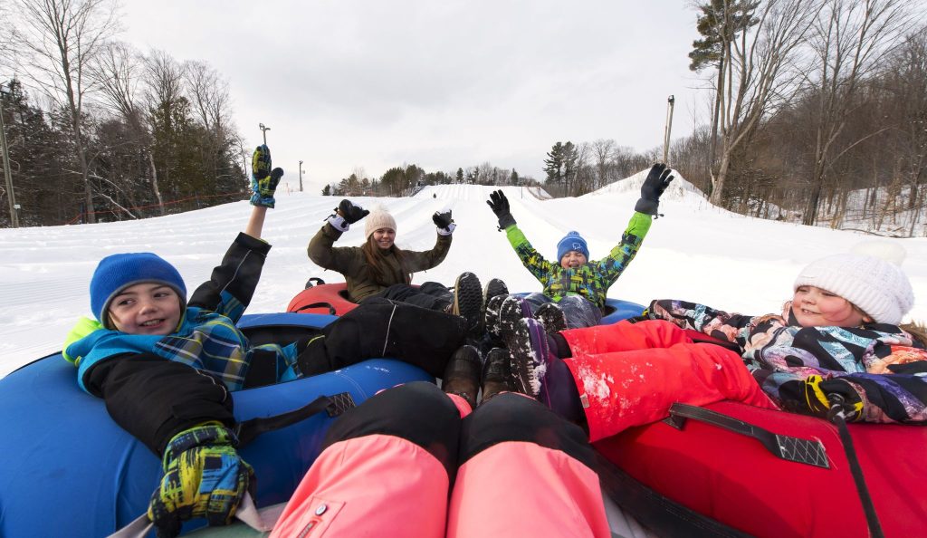 Family snow tubing together down a snowy hill