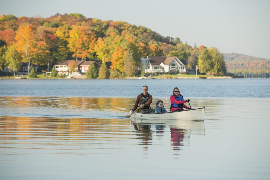 Two people canoeing on a lake surrounded by fall colours