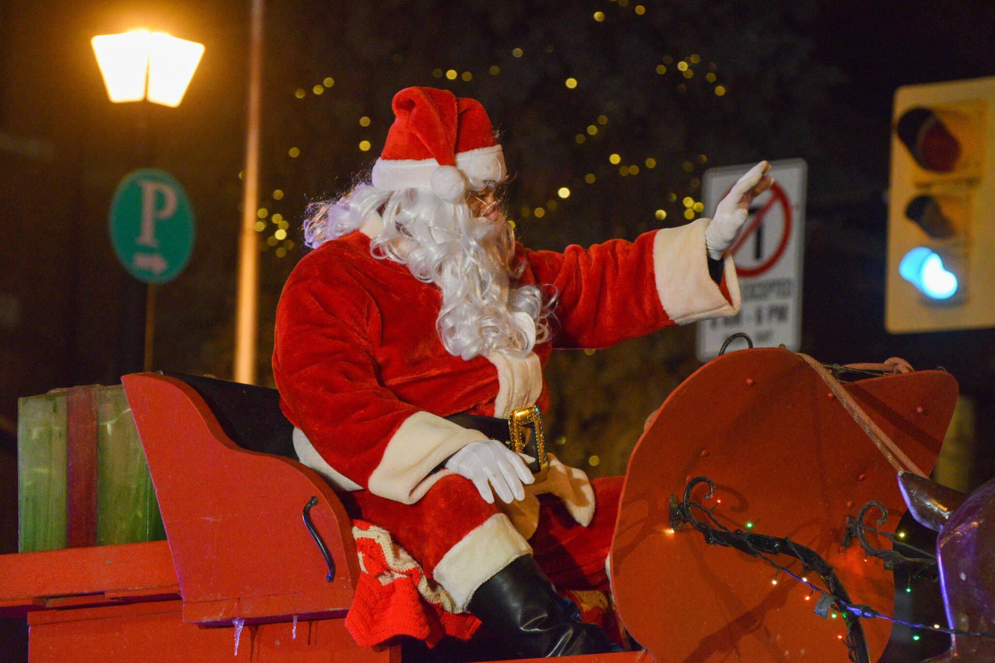 Santa Claus riding in a parade sleigh at night