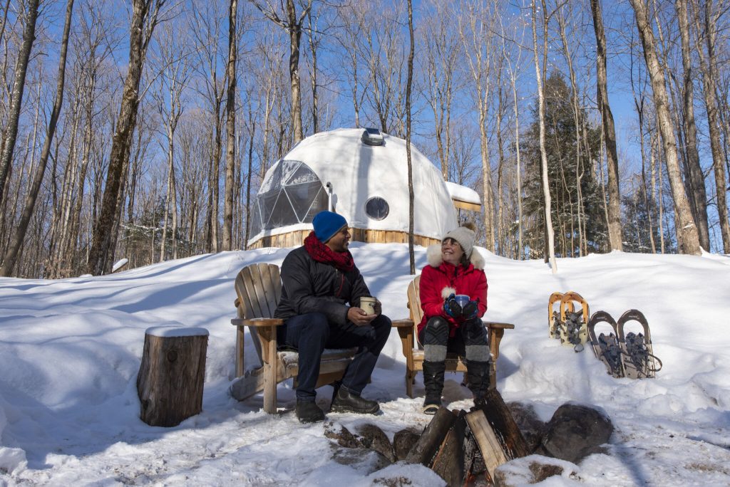 Visitors with sled dogs beside a geodesic dome in winter