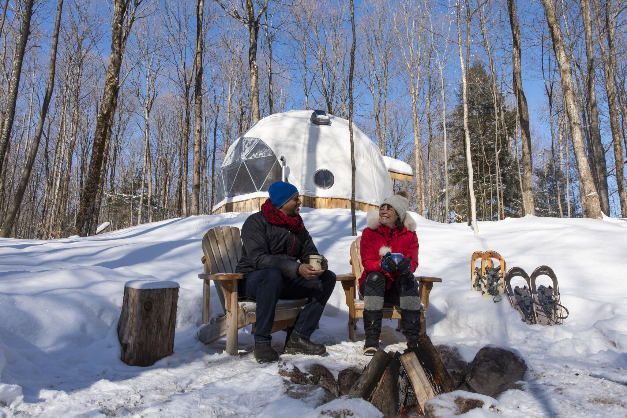 Visitors with sled dogs beside a geodesic dome in winter