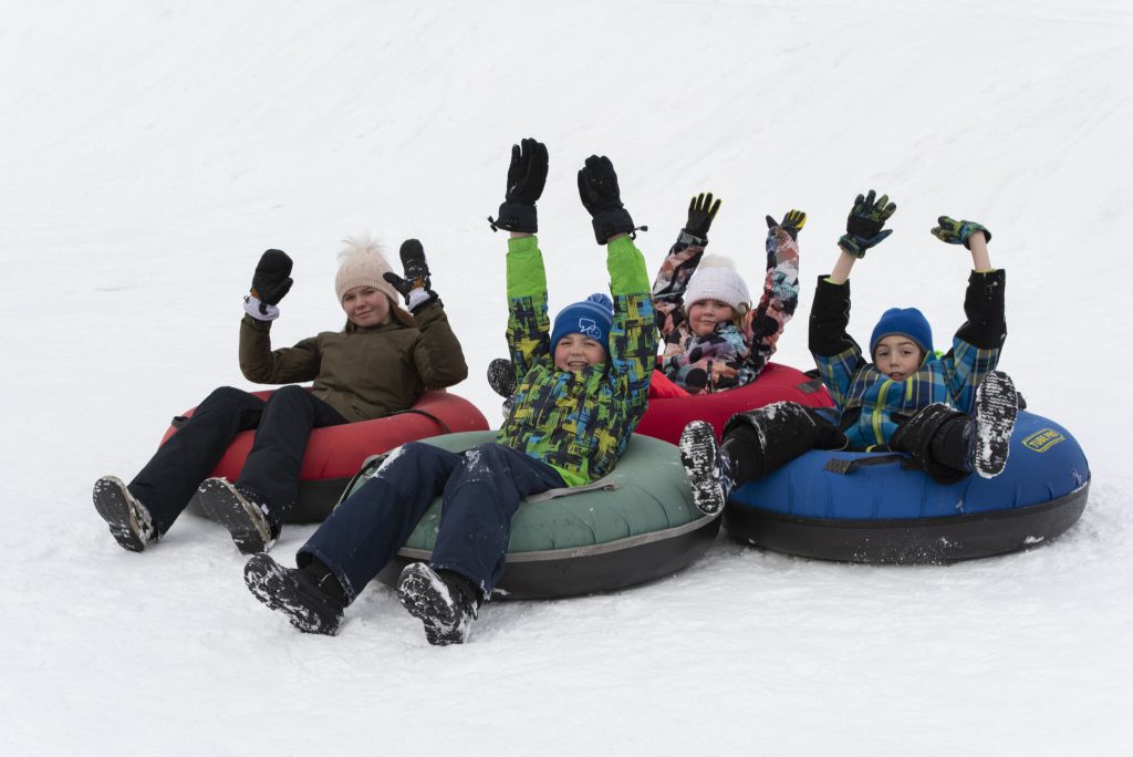 Family snow tubing together down a snowy hill