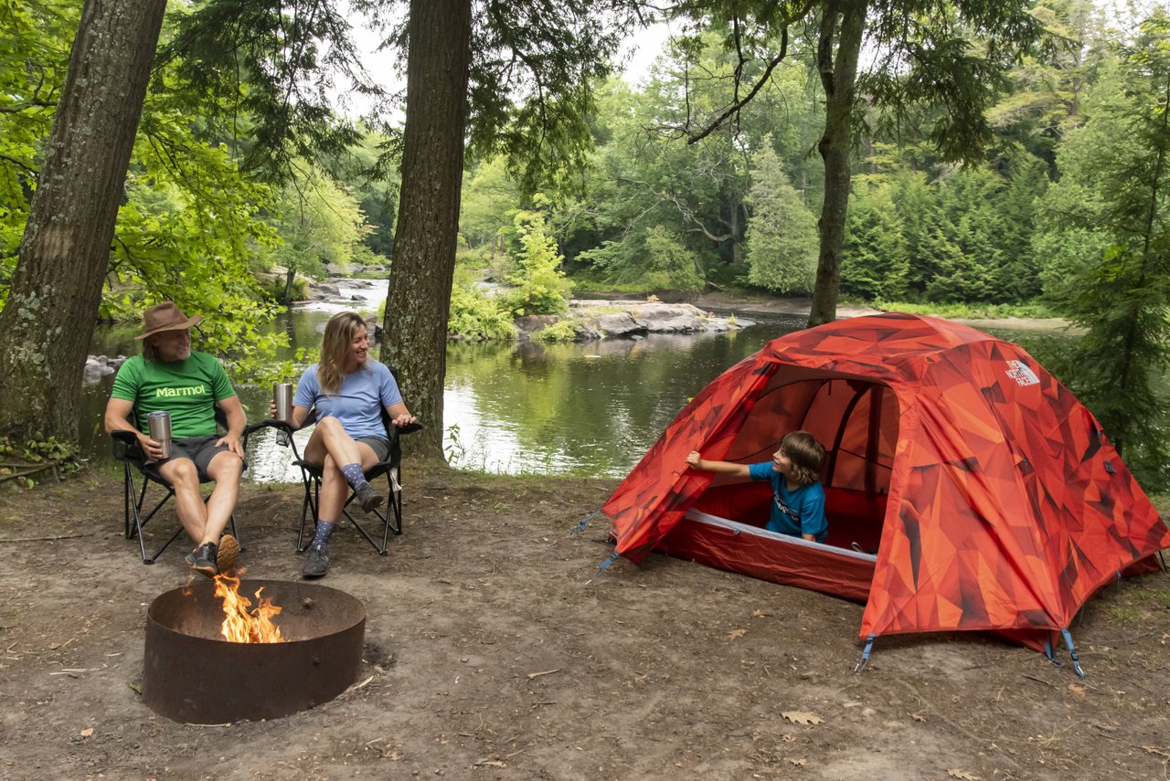 Family campsite with a red tent beside the river