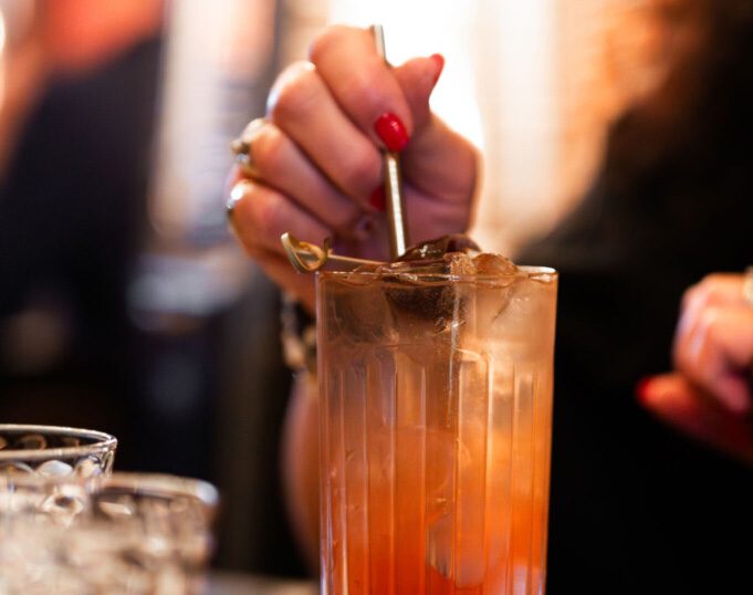 Bartender stirring an orange cocktail