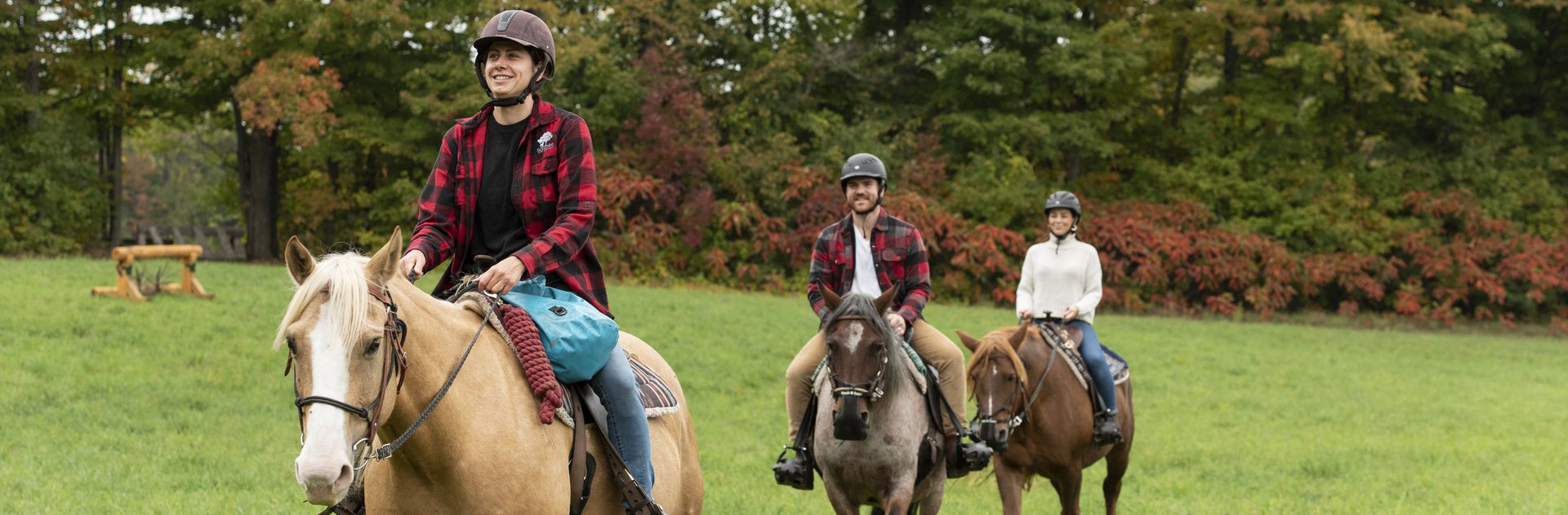 Horseback riders crossing a grassy field